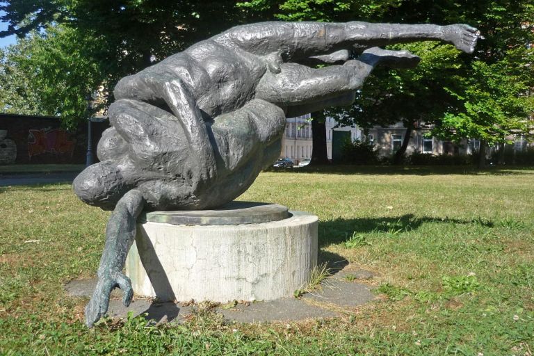 auf der Wiese steht die Plastik Ringende auf einem kreisrunden Betonsockel